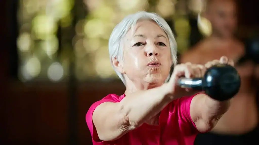 Toning Arms After 60: Empowering Womens Fitness Through Effective Weight Training 1 Older woman doing weight training Warwickshire to help her strength and longevity