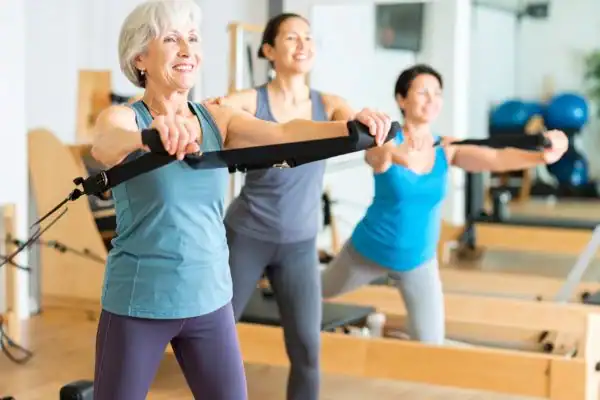 Toning Arms After 60: Empowering Womens Fitness Through Effective Weight Training 2 older woman doing weight training Warwickshire and resistance in the gym to tone upper arms